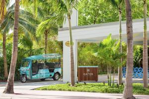 un carrito de golf azul estacionado junto a un edificio con palmeras en The Gates Hotel South Beach - a Doubletree by Hilton, en Miami Beach
