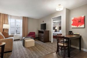 a hotel room with a desk and a bedroom at Homewood Suites Rochester-Henrietta in Henrietta