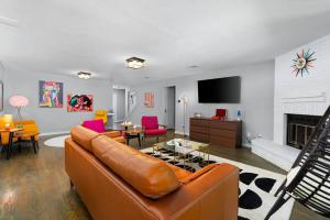 a living room with a brown leather couch and a fireplace at That 70s House -Fun 6 Bedroom W Pool & Game Room in Round Rock
