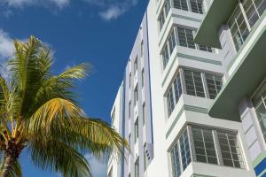 un bâtiment blanc avec un palmier en face dans l'établissement The Gabriel Miami South Beach, Curio Collection by Hilton, à Miami Beach