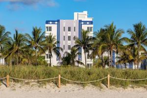 a building with palm trees in front of a beach at The Gabriel Miami South Beach, Curio Collection by Hilton in Miami Beach