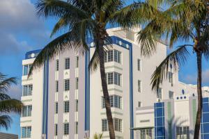 un bâtiment blanc avec des palmiers devant lui dans l'établissement The Gabriel Miami South Beach, Curio Collection by Hilton, à Miami Beach