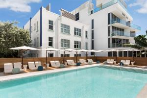 einen Pool mit Stühlen und Sonnenschirmen neben einem Gebäude in der Unterkunft The Gabriel Miami South Beach, Curio Collection by Hilton in Miami Beach