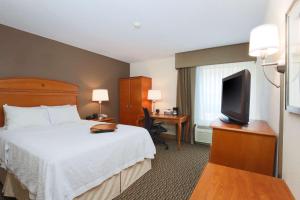 ein Hotelzimmer mit einem Bett und einem Flachbild-TV in der Unterkunft Hampton Inn Decatur/Forsyth in Forsyth