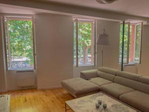 a living room with a couch and two windows at Superbe Appartement au bord de la Garonne Toulouse in Toulouse