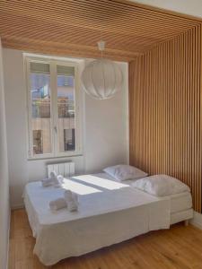 a bedroom with a large white bed with a wooden ceiling at Superbe Appartement au bord de la Garonne Toulouse in Toulouse
