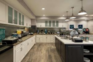 a large kitchen with white cabinets and wooden floors at Homewood Suites by Hilton Erie in Erie