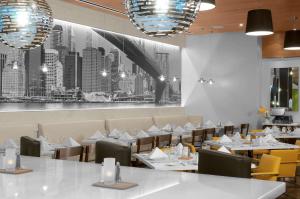 un restaurante con mesas y sillas blancas y una foto de la ciudad en Hilton Garden Inn New York - Times Square Central, en Nueva York