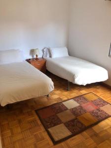 a bedroom with two beds and a rug at Apartamento Padrón Centro P5 by UR in Padrón