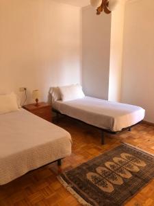 a bedroom with two beds and a rug on the floor at Apartamento Padrón Centro P5 by UR in Padrón