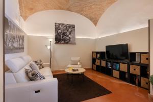 a living room with a white couch and a tv at Hotel Ristorante Borgo Antico in Monteroni dʼArbia