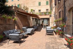 Hotel Ristorante Borgo Antico في مونتيروني دي اربيا: مجموعة من الكراسي والطاولات على رصيف من الطوب