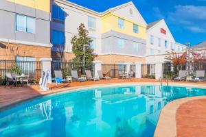 una piscina en un hotel con sillas y un edificio en Hilton Garden Inn Norman en Norman