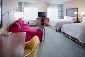 pokój hotelowy z 2 łóżkami i czerwoną kanapą w obiekcie Hampton Inn & Suites Palmdale w mieście Palmdale