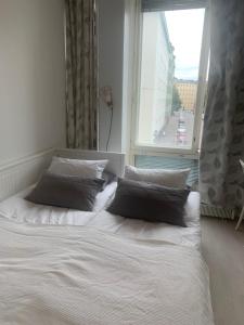 a bed with two pillows in front of a window at Idas AirBnB in Helsinki