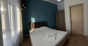 1 dormitorio con cama blanca y pared azul en Уютная и комфортная 3х комнатная квартира со всеми условиями, en Uralsk