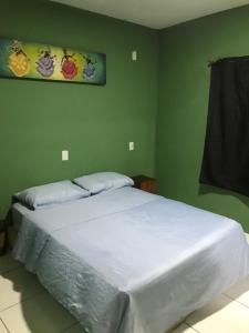 een slaapkamer met een wit bed in een groene muur bij Hostel do Rasta in Salvador
