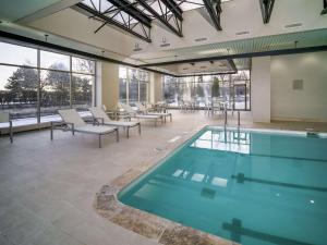 a swimming pool in a building with tables and chairs at Embassy Suites by Hilton Detroit Troy Auburn Hills in Troy