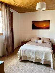 a bedroom with a bed with a sunset picture on the wall at Vv Casa Maye Pepa en Teror in Teror