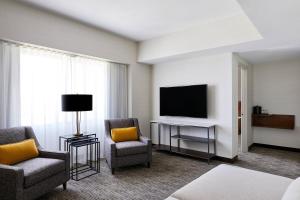 a hotel room with a television and two chairs and a table at Delta Hotels by Marriott Phoenix Mesa in Mesa