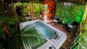 a large bath tub in a room with plants at Bungalows Las Iguanas Arenal Volcano in Fortuna