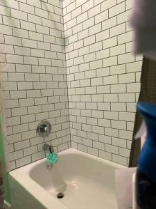 a white tiled shower with a bath tub with a sink at Cosy 3-Bedroom Downtown Walk to Convention Center in Tampa +32 photos