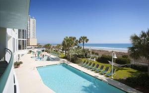 uma vista para uma piscina com cadeiras e para a praia em Hampton Inn & Suites Myrtle Beach Oceanfront em Myrtle Beach