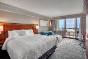 a hotel room with a bed and a balcony at Courtyard by Marriott Jacksonville Beach Oceanfront in Jacksonville Beach