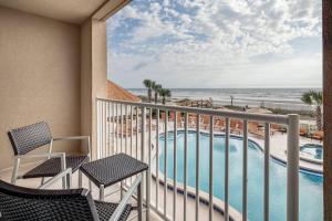 uma varanda com cadeiras e uma piscina e a praia em Courtyard by Marriott Jacksonville Beach Oceanfront em Jacksonville Beach