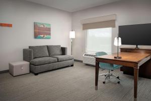 ein Wohnzimmer mit einem Sofa und einem Schreibtisch mit einem Computer in der Unterkunft Hampton Inn & Suites Portland/Hillsboro-Evergreen Park in Hillsboro