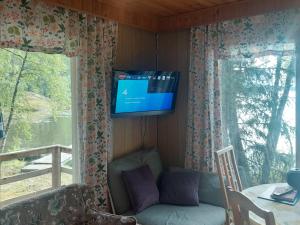 a living room with a couch and a tv on the wall at Lakeside Hilda, rantamökki 