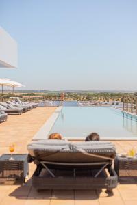 two people laying in lounge chairs next to a swimming pool at Sleep & Nature Hotel in Lavre