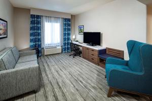 Cette chambre d'hôtel dispose d'un canapé, d'un bureau et d'une télévision. dans l'établissement Hilton Garden Inn San Diego/Rancho Bernardo, à Rancho Bernardo