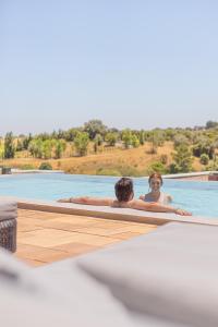 two people swimming in a swimming pool at Sleep & Nature Hotel in Lavre