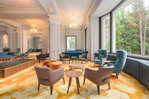 a lobby with chairs and tables and windows at Hotel Reine Victoria in St. Moritz