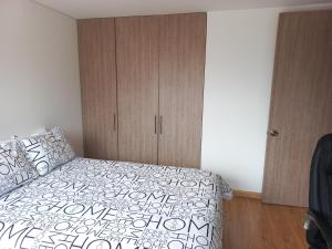 een slaapkamer met een bed en een houten kast bij Hermoso, Apacible - Apartamento Central - Tunja in Tunja