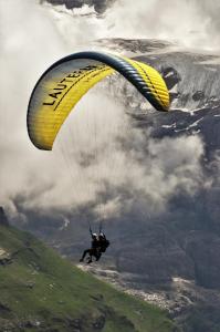 a person is flying in the air with a parachute at Ferienwohnung Talhaus in Lauterbrunnen