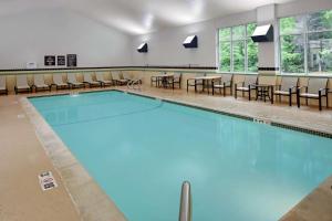 una piscina con sillas y mesas en una habitación en Homewood Suites by Hilton - Boston/Billerica-Bedford, en Billerica