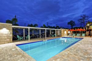 uma piscina à noite com mesas e cadeiras em Home2 Suites By Hilton Daytona Beach Speedway em Daytona Beach