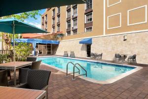 a swimming pool with chairs and a table and a building at Hampton Inn & Suites Fort Lauderdale Airport in Hollywood