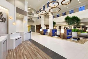 un vestíbulo de oficina con sillas azules y una gran lámpara de araña en Embassy Suites Portland/Hillsboro en Hillsboro