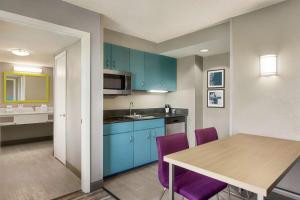 a kitchen with blue cabinets and a table with purple chairs at Hampton Inn & Suites Fort Lauderdale Airport in Hollywood