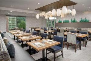 un restaurante con mesas de madera y sillas azules en Hilton Garden Inn Westchester Dobbs Ferry, en Dobbs Ferry