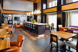 a restaurant with a bar and tables and chairs at Hampton Inn & Suites Lansing West in Lansing