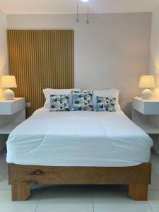 ein Schlafzimmer mit einem großen weißen Bett mit blauen Kissen in der Unterkunft Villa Brise de Mer in Las Terrenas