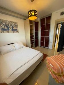 a bedroom with a white bed and a chandelier at Roy Vacation Home in Rishon LeẔiyyon