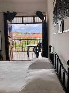sypialnia z łóżkiem oraz balkon ze stołem w obiekcie Tarrafal Ecodécor Rooms w mieście Tarrafal
