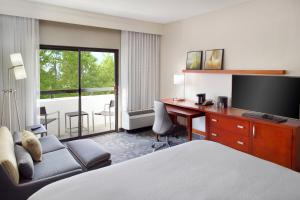 Habitación de hotel con cama y escritorio con TV. en Courtyard by Marriott Perimeter Center, en Atlanta