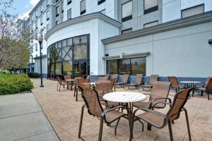 un patio avec des tables et des chaises en face d'un bâtiment dans l'établissement Hampton Inn & Suites Newark-Harrison-Riverwalk, à Newark