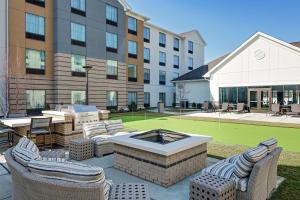 un patio avec des chaises et un foyer extérieur en face d'un bâtiment dans l'établissement Homewood Suites By Hilton Ronkonkoma, à Ronkonkoma